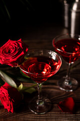 Delicious refreshing beverage drink red cocktail with red rose and petals on wooden table. Romantic, Valentines day concept.