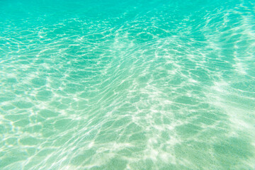 Wavy and sandy seabed in Fernando de Noronha with sun reflections on the water surface