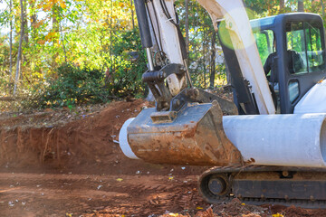 Worker who use tractor to lift concrete sewage pipes in ground are being prepared for underground installation