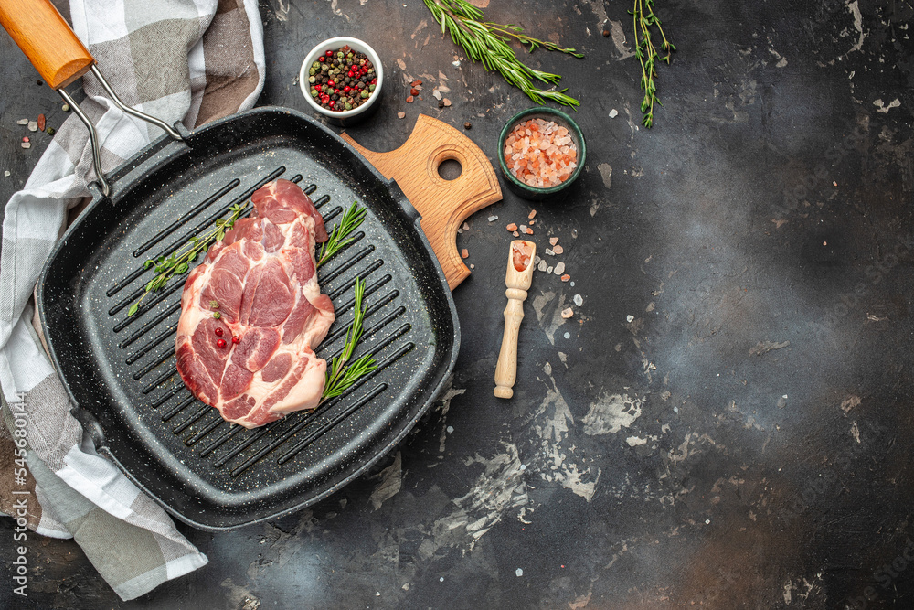 Wall mural raw pork meat in the pan with rosemary and pepper on a dark background. long banner format. top view