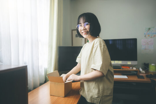 Young adult asian woman open box package from deliverly shopping service