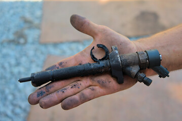 Removed old nozzle from a diesel engine on a hand