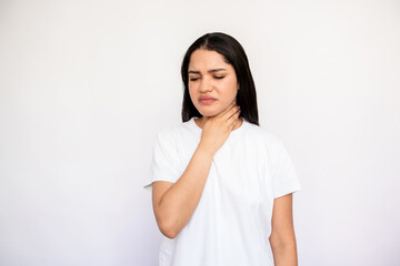 Portrait of displeased young woman touching her throat over white background. Caucasian lady wearing white T-shirt suffering from tonsillitis. Pulmonary diseases concept