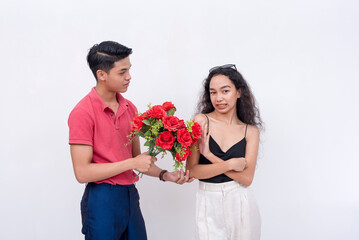 A young woman rebuffs a suitor bringing a bouquet of red flowers. Uninterested and annoyed girl....