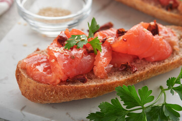 Sandwiches with salted salmon. Open sandwiches from cereal or whole grain rye bread with salted salmon, sesame seeds and dried tomato on white marble stand. Seafood. Healthy food. Scandinavian cuisine