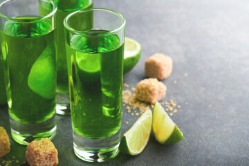 Absinthe. Two glasses of absinthe with cane sugar and lime on dark background. Strong alcoholic drink. Bar card concept. Place for text.