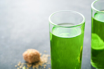 Absinthe. Two glasses of absinthe with cane sugar and lime on dark background. Strong alcoholic drink. Bar card concept. Place for text.