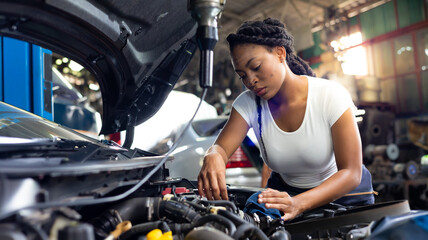 Charge electric power to ca battery by charging jumper cables. African mechanic female uses multimeter voltmeter to check voltage level in car battery at car service and maintenance garage.