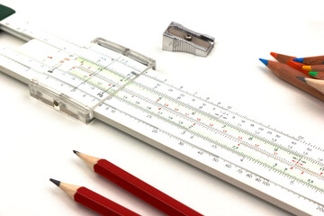 slide rule being used for calculation with pencils and sharpener isolated on white background.
