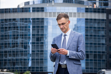 Business man with a phone in his hands on the background of the building