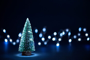 Christmas small tree on dark background and bokeh lights, copy space