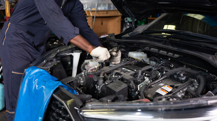 Close up hand black male mechanic repairs car in garage. Car maintenance and auto service garage concept.