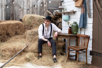 country groom in a black hat and white shirt in the village. Country wedding
