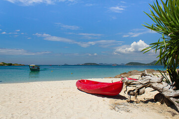 Red kayak on beach with blue sea and sky background