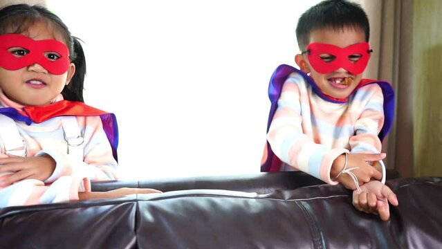 Little brother and sister in superhero costumes happy in home