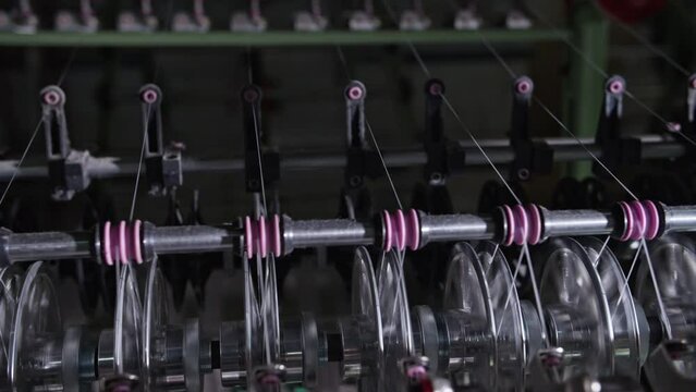 Close up of textile machine in slow motion. Fibre thread lines on the weaving loom machine. A loom machine for clothing or woven clothes. Weaving machine for garment industry.