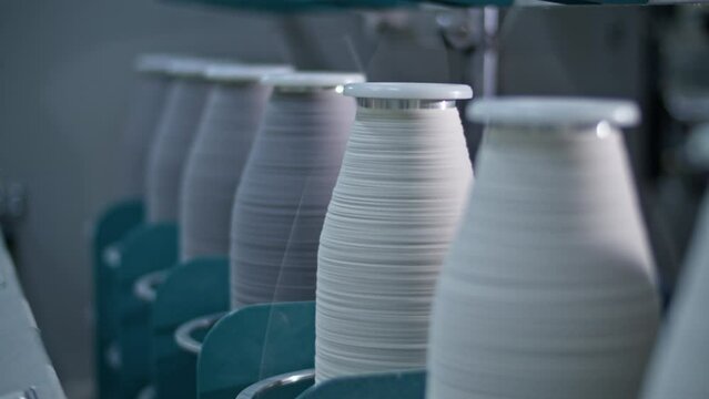 Cotton yarn on bobbin. Spool of thread closeup on clothing factory. Textile fabric. Industrial equipment. Knitwear production