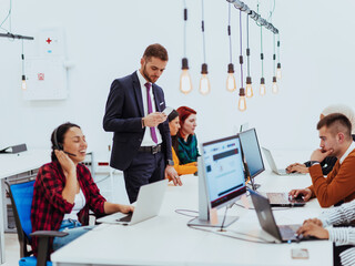 Group of multi-ethnic colleagues working on desktop computers, laptop and sharing their ideas in a modern office space.Young influencers work on online marketing projects.