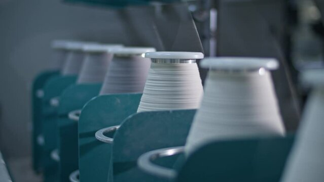 Cotton yarn on bobbin. Spool of thread closeup on clothing factory. Textile fabric. Industrial equipment. Knitwear production