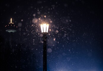 Closeup shot a street lamp glowing in the dark during a snowfall