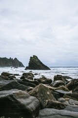 Vertical shot of the Aguilar beach at low tide with the rocks in the water in Asturias, Spain