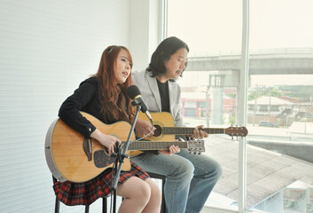 two artist play music in academy studio classroom in the urban, a man play acoustic guitar and a girl sing a song. concept for musician lifestyle,music education academy