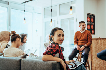 Group of multi-ethnic colleagues working on desktop computers, laptop and sharing their ideas in a modern office space.Young influencers work on online marketing projects.