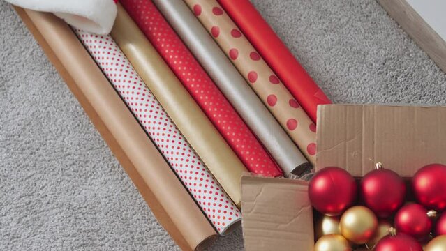 Girl in a Santa hat creates New Year's packages from red wrapping paper. Young woman is packing Christmas presents for her friends and relatives. Decorations, preparation for the winter holiday season