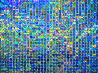 Wall is decorated with round plates. Iridescent background. Colorful texture. Multicolored pattern. Blue plates shimmer in different colors. Background for decoration. Abstract multicolored texture