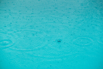 Regentropfen auf der Wasseroberfläche eines Pools