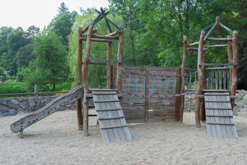 Wooden slide with steps and a bridge on the playground for children. An empty wooden playground built for children in the park.