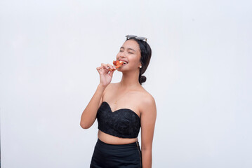 A young asian woman enjoys a tasty chicken wing. Isolated on a light background.