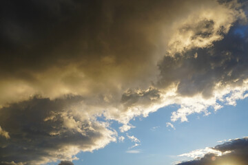 Fototapeta na wymiar Dramatic sky with gray cloud lit by sun with part of blue sky