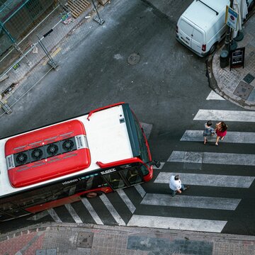 Aerial view of a city bus in Valencia taken from a balcony, and people crossing the street