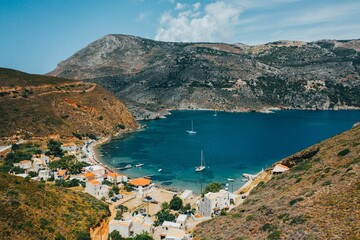 Naklejka premium Scenic mountains and blue sea port with sailing boats in Porto Kagio, Mani, Greece
