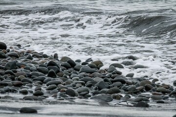 Gray scale shot of the beach shore full of small rocks