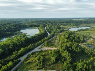 Aerial view of greenery field surrounded by dense trees and water