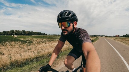 Closeup of a caucasian bicycle rider on the road taking a selfie during the ride.