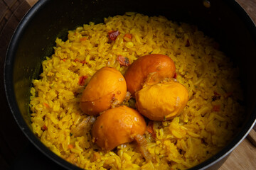 Close em uma panela preta com arroz com pequi sobre uma tábua de madeira. Um prato típico brasileiro.