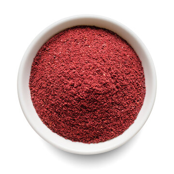 Dry ground sumac in white bowl isolated on white. Top view.