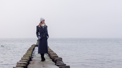 Woman on Groynes in the German Baltic Sea during winter - obrazy, fototapety, plakaty