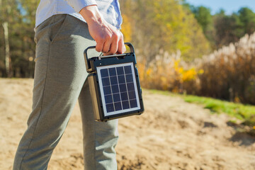 The guy is carrying a portable solar charging station in his hands. Eco-friendly energy for camping...