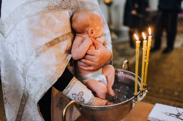A male Christian priest in a church conducts a sacred rite, a ritual for a beautiful newborn,...