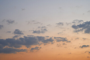 The blue sky is orange and the clouds are soft when the sun is about to set.