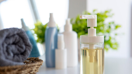 Liquid soap bottle, gray towel on basket in bathroom. Hygiene and healthy life concept. Close up, selective focus