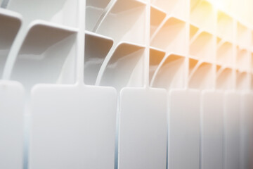 Obraz premium New bimetallic sectional heating radiator for home and room. Close-up of solar-lit heating battery. Promotional photo. Coziness and warmth in house. Background