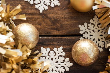 Golden Christmas balls with gold tinsel and snowflakes on wooden background