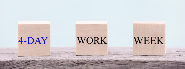 4 day working week words on wooden cube on blue background. reducing burnout and stress levels concept. copy space banner