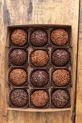 Box with several brigadeiros lined up on wooden table. Brazilian traditional sweet.