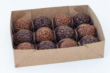 Box with several brigadeiros lined up on white background. Brazilian traditional sweet.